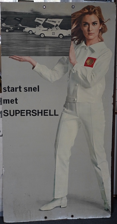 Automobilia interest; a 1970s card advertising sign for Shell Oil Supershell featuring a portrait of Alexandra Bastedo in a white suit with Shell logo, 157.5 x 80.5cm. Condition fair, some damage to the edges.